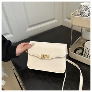 Detailed view of a white vintage shoulder bag featuring a gold metal twist lock buckle