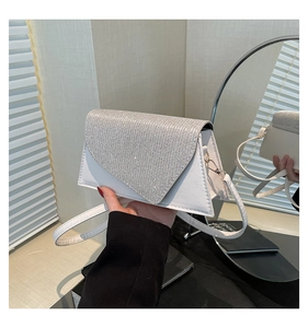Détail d'un sac bandoulière blanc en similicuir avec rabat triangulaire en strass brillants