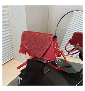 Détail du rabat pailleté rouge du sac à bandoulière avec surpiqûres et boucle métallique