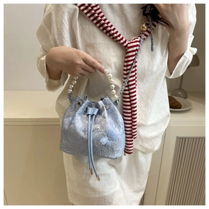 Detail of light blue lace bucket bag with 3D butterfly accents and pearl handle