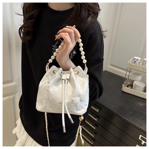 Detail of white lace bucket bag featuring 3D butterfly embroidery and pearl handle