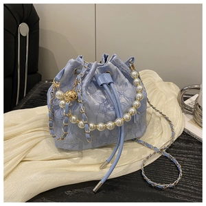 Close-up of light blue jacquard bucket bag with pearl handle and metal chain details