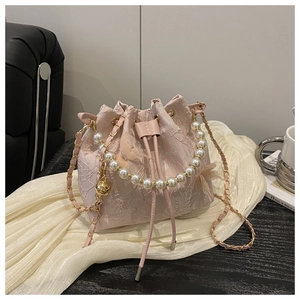 Detail of pink lace bucket bag with pearl handle and floral embroidery on soft fabric