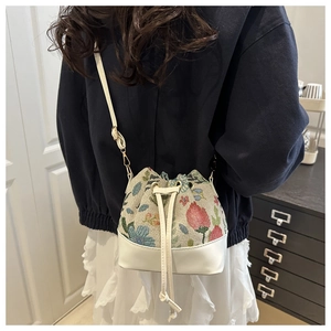 Ethnic embroidered bucket bag with drawstring closure and white faux leather strap