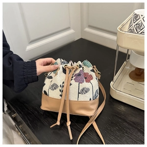 Close-up of drawstring bucket bag with floral jacquard fabric and brown leather details