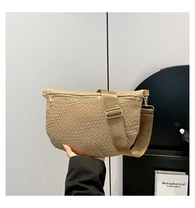 Détail du sac bandoulière beige tressé avec large sangle en tissu et fermeture dorée