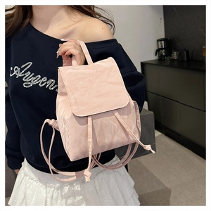 Detail of light pink mini backpack featuring unique pleated texture and drawstring closure