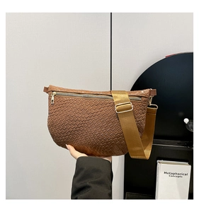 Détail de la texture tressée marron du sac bandoulière avec une sangle en nylon