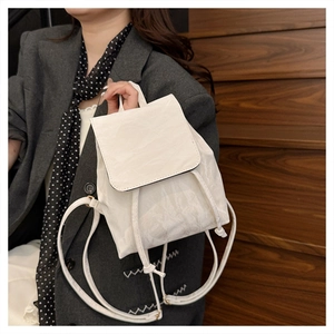 Detail of white textured mini backpack with drawstring and flap closure on model