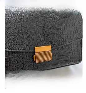 Close-up of black crocodile embossed leather texture with vintage gold metal buckle