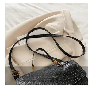 Detail of adjustable leather strap with gold buckle on black crocodile handbag