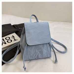 Detail of light blue vintage backpack with drawstring closure and wrinkled leather texture