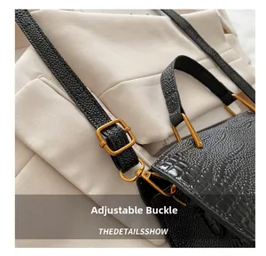 Close-up of black crocodile embossed leather bag with vintage gold adjustable buckle