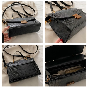 Detail view of black crocodile pattern shell bag showing texture, interior and metal lock