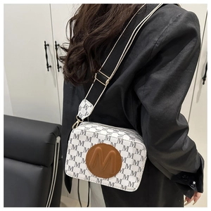 Macro detail of camera bag featuring monogram print and adjustable jacquard shoulder strap