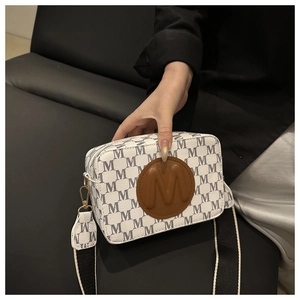 Detail of camera bag with M-pattern leather and adjustable wide fabric strap