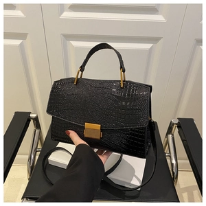 Close-up of black crocodile embossed leather handbag with vintage gold metal buckle detail
