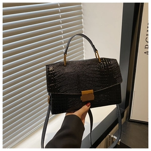 Detail of glossy black crocodile embossed texture and golden square twist lock buckle