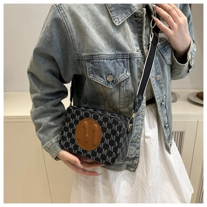 Detail of crossbody camera bag with monogram M pattern and wide striped shoulder strap