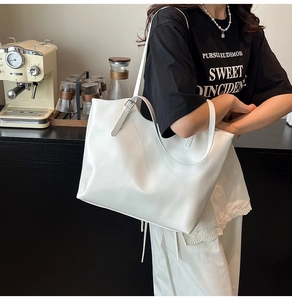 Dettaglio della borsa tote bianca con trama in pelle lucida e tracolla regolabile