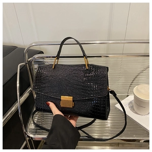Close-up of black crocodile pattern leather bag with golden metallic lock and handle