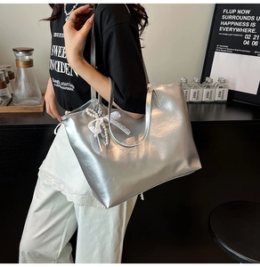 Silver large capacity tote bag featuring lace bow and pearl charm worn by a model