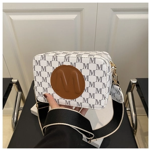 Detailed view of camera bag with monogram print, leather logo patch and striped strap