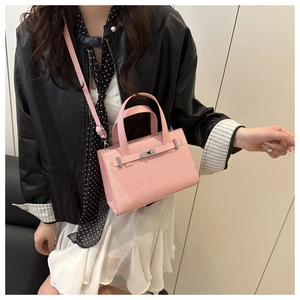 Close-up of pink litchi grain leather handbag featuring silver twist lock and handle