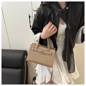 Detail of lychee pattern leather handbag with metallic rotating lock and strap