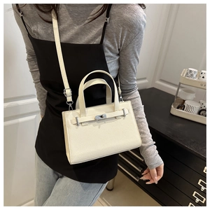 Detail of off-white lychee texture leather handbag with metallic turn-lock closure