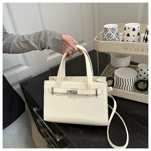 Detail of cream lychee texture leather handbag with metal turn-lock and stitching