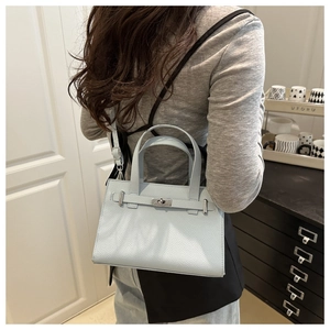 Crossbody view of light blue lychee pattern leather handbag with silver metal buckle
