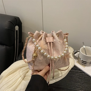 Pink lace bucket bag with pearl handle and butterfly tulle detail shown in hand
