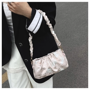 Detail of elegant pleated satin shoulder bag with traditional floral jacquard patterns