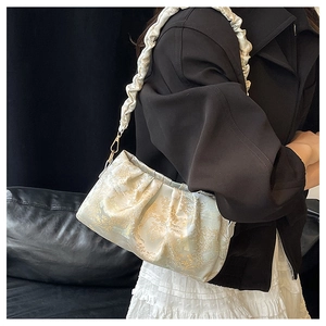Detail of a white silk jacquard shoulder bag with cloud-pleated strap and golden patterns
