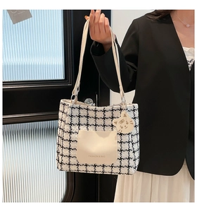 Detail of black and white houndstooth tote bag with cream pocket and tiger charm