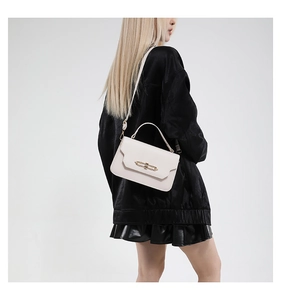 Chic off-white leather shoulder bag with gold metal buckle shown on a model