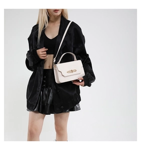 Detail of a white leather handbag with a gold metal clasp and single handle for women