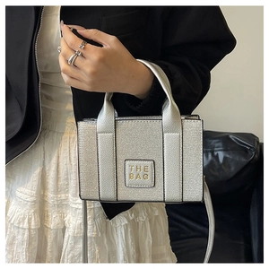 Détail du mini cabas argenté avec texte THE BAG et doubles poignées supérieures