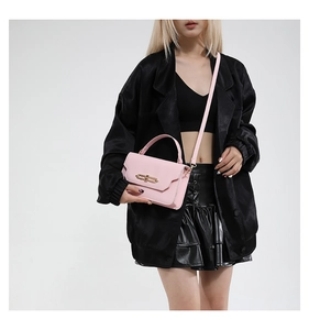 Detail of pink crossbody bag with gold metal buckle worn with a black outfit