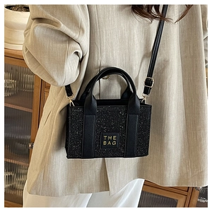 Close-up of black sequin mini tote bag with THE BAG inscription and leather handles