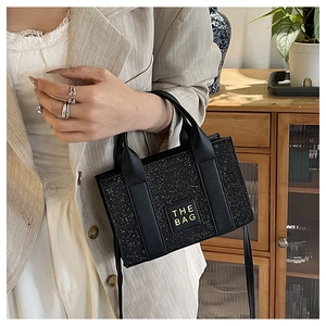 Detail einer schwarzen Glitzertasche mit Ledergriffen und THE BAG Logo Aufdruck