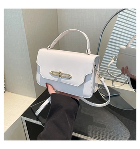 Detail of white rectangle flap bag with elegant gold metal bar buckle and smooth texture