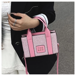 Vue détaillée d'un mini sac en tweed rose avec patch THE BAG porté par un mannequin