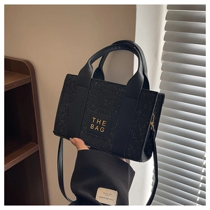 Détail d'un sac cabas noir pailleté avec doubles poignées et étiquette logo