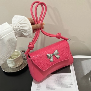 Stylish pink shoulder bag with woven texture, silver bow detail, and knotted rope handle