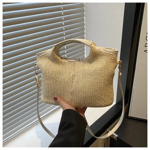 Detail of hand-woven straw tote with leather handles and gold-tone hardware for summer