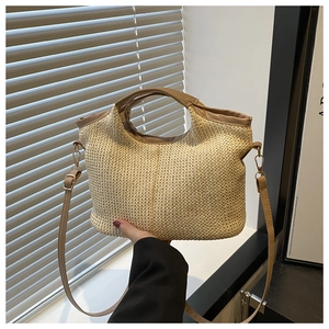 Detail of beige woven tote bag with brown PU leather handles and metal strap attachments
