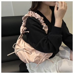 Détail du sac à bandoulière rose avec grands nœuds et bandoulière plissée