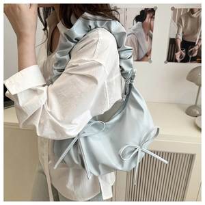 Detail of the light blue shoulder bag with ruffled straps and decorative bow accents